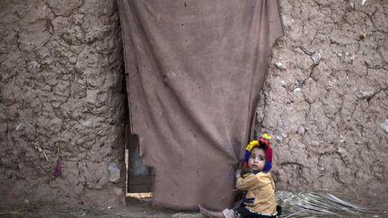 Une jeune r&eacute;fugi&eacute;e afghane s'aggrippe &agrave; la porte de sa maison de fortune dans la banlieue d'Islamabad (Pakistan), le 12 novembre 2013. (MUHAMMED MUHEISEN / AP / SIPA)