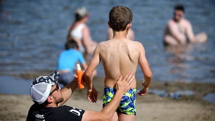 Un père enduit son fils de crème solaire pour le protéger du soleil. Un geste qui n'est pas anodin, selon Agir pour l'Environnement (photo d'illustration). (MARQUET FR?D?RIC / MAXPPP)