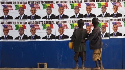 Des enfants regardent un mur recouvert des affiches repr&eacute;sentant les pr&eacute;sidents Barack Obama et Macky Sall, &agrave; Dakar (S&eacute;n&eacute;gal), le 26 juin 2013.&nbsp; (JOE PENNEY / REUTERS)