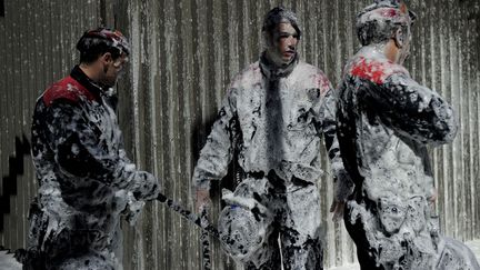 Des membres de la police r&eacute;gionale catalane sont recouverts de neige carbonique pendant une manifestation de pompiers &agrave; Barcelone (Espagne), le 14 mars 2013. (JOSEP LAGO / AFP)