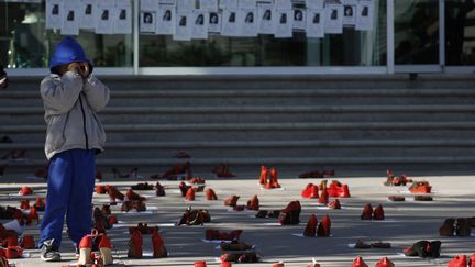 Un gar&ccedil;on marche parmi des chaussures rouges plac&eacute;es devant le bureau du procureur g&eacute;n&eacute;ral de Ciudad Juarez, au Mexique, en hommage aux femmes victimes de violences, le 10 d&eacute;cembre 2012.&nbsp; (REUTERS)