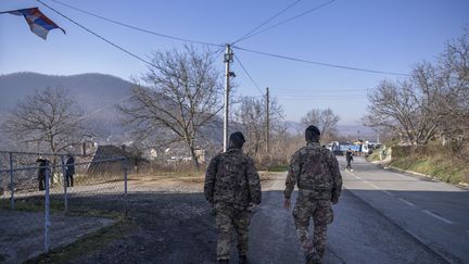 Deux soldats de la KFOR, la force armée multinationale mise en œuvre par l'OTAN, patrouillent sur une route barricadée par des Serbes, près de Zvecan au Kosovo, le 26 décembre 2022. (ARMEND NIMANI / AFP)