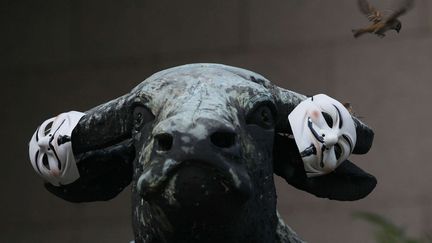 Quelque mois plus tard, accroch&eacute; au taureau de Wall Street, le masque de Guy Fawkes devient le symbole des protestataires du mouvement "Occupy". (KIN CHEUNG / AP / SIPA)