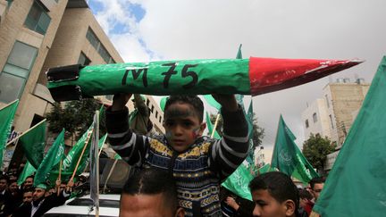 Un enfant palestinien porte l'effigie d'une roquette artisanale de type M75, lors du 25e anniversaire de la cr&eacute;ation du Hamas, le 14 d&eacute;cembre 2012 &agrave; H&eacute;bron (Cisjordanie). (HAZEM BADER / AFP)