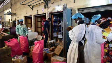 Un policier observe des employés du ministère de la Santé en train de vider des magasins vendant de faux médicaments lors d'une descente le 3 mai 2017 au marché Adjame à Abidjan dans le cadre de la lutte contre les médicaments contrefaits.&nbsp; (Issouf Sanogo / AFP)