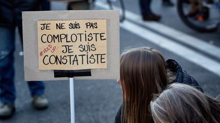 Une manifestante et sa pancarte lors de la&nbsp;marche des libertés, à Paris, le 28 novembre 2020. (MARTIN NODA / HANS LUCAS VIA AFP)