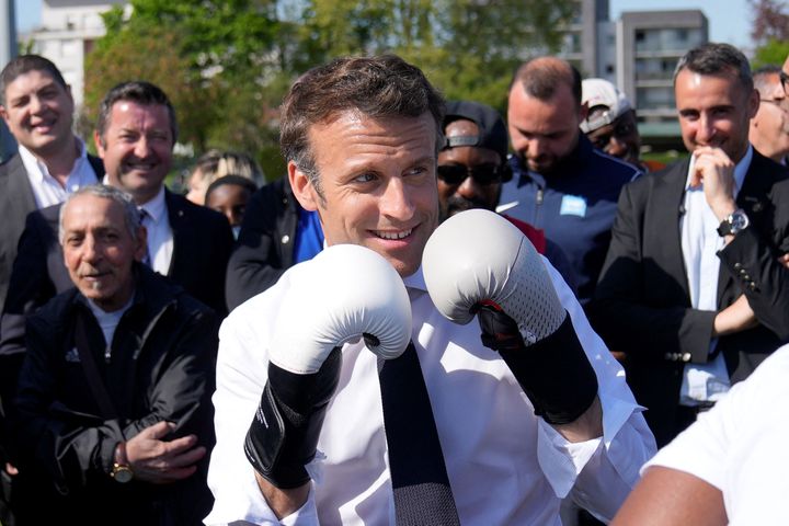 Emmanuel Macron enfile des gants de boxe, le 21 avril 2022, lors d'un déplacement à&nbsp; Saint-Denis (Seine-Saint-Denis). (FRANCOIS MORI / AFP)