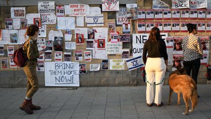 Des Israéliens se tiennent devant des photographies de personnes prises en otage par le Hamas, le 20 octobre 2023 à Tel-Aviv (Israël). (GILI YAARI / NURPHOTO / AFP)