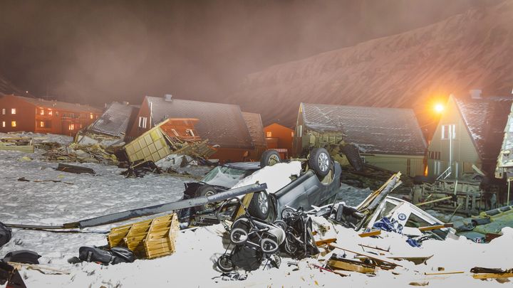 Une voiture renversée et des débris jonchent le sol enneigé, devant des maisons déplacées sur plusieurs dizaines de mètres, le 7 janvier 2016, à Longyearbyen, plus de deux semaines après une avalanche meurtrière. (HEIKO JUNGE / NTB SCANPIX MAG / AFP)