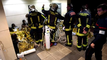 Les pompiers de Paris secourent des victimes de l'incendie d'un foyer de travailleurs immigrés, à Boulogne-Billancourt, le 16 décembre 2016. (JULIEN DUC / BRIGADE DES SAPEURS POMPIERS DE PARIS / AFP)