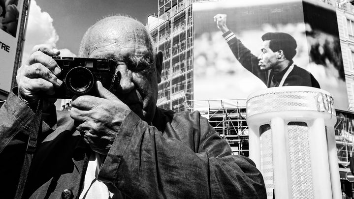 Raymond Depardon devant sa photographie de 1968 de Lee Evans, vainqueur du 400 mètres, poing levé pour manifester sa colère contre les discriminations raciales. (CHRISTOPHE AIRAUD)