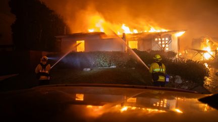 Des pompiers tentent d'éteindre les flammes d'une maison incendiée, à Los Angeles, le 8 janvier 2025. Le quartier accueille de nombreuses villas à plusieurs millions de dollars où habitent des célébrités hollywoodiennes. (APU GOMES / GETTY IMAGES NORTH AMERICA / AFP)