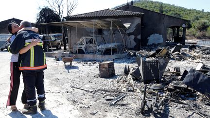 Une femme enlace un pompiers devant une maison incendiée, à Bormes-les-Mimosas (Var), mercredi 26 juillet 2017.&nbsp; (JEAN-PAUL PELISSIER / REUTERS)