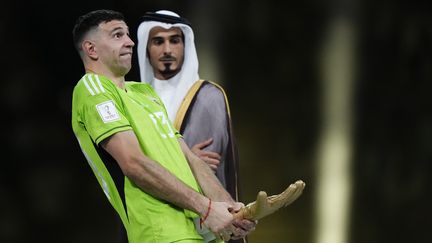 L'Argentin Emiliano Martinez choisit une façon originale de brandir son trophée de meilleur gardien de la Coupe du monde, le 18 décembre 2022, à Doha (Qatar). (JOSE BRETON / NURPHOTO / AFP)