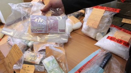 Un officier de police montre de l'argent et de la drogue saisis le 17 septembre 2013 &agrave; Nice (Alpes-Maritimes). (JEAN-CHRISTOPHE MAGNENET / AFP)