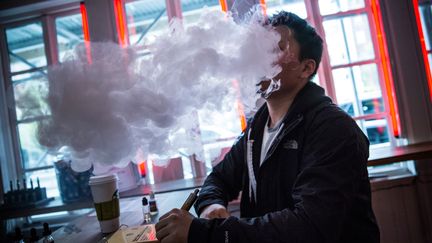 Un homme fume une cigarette &eacute;lectronique dans un bar, le 29 avril 2014, &agrave; New York. (ANDREW BURTON / GETTY IMAGES NORTH AMERICA / AFP)