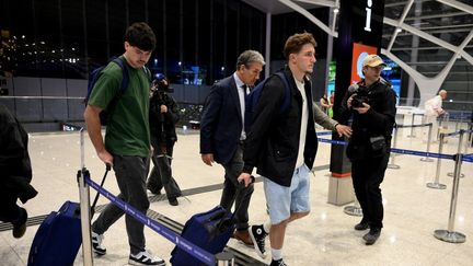 Les rugbymen Hugo Auradou (gauche) et Oscar Jegou (droite), accompagné d'un de leurs avocats, embarquent à l'aéroport de Buenos Aires (Argentine), le 3 septembre 2024. (LUIS ROBAYO / AFP)