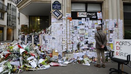 Un homme se recueille devant un mémorial improvisé à proximité de l'ancienne rédaction de "Charlie Hebdo", à Paris, quelques jours après l'attaque du 7 janvier 2015. (BERTRAND GUAY / AFP)