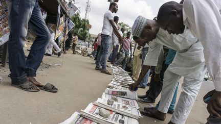 Des Nigérians lisent les gros titres de la presse dans la capitale, Abuja. (STEFAN HEUNIS / AFP)