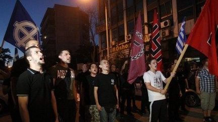 Défilé de l'Aube dorée en juin 2012 à Thessalonique avec le drapeau du parti (sorte de croix noire sur fond rouge) et le drapeau "occident" en blanc sur fond noir. (AFP PHOTO / SAKIS MITROLIDIS)