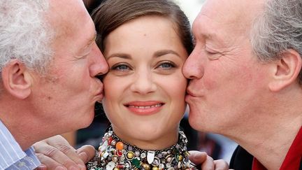 Luc et Jean-Pierre Dardenne entourent Marion Cotillard, l'héroïne de leur nouveau film "Deux Jours, Une Nuit ", présenté en sélection, officielle.  On remarquera l'étonnante robe tout en boutons de la comédienne. 
 (VALERY HACHE / AFP )