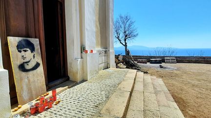 
Une peinture au pochoir représentant Yvan Colonna devant l'église de Cargèse, avant les funérailles de l'activiste indépendantiste, le 25 mars 2022. (Benjamin Illy/Radio France)