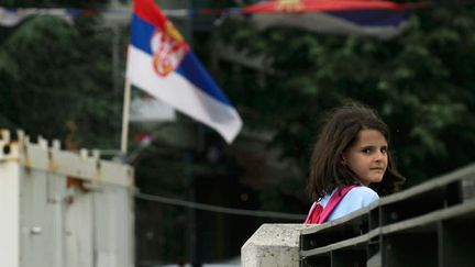 &nbsp; (Une jeune albanaise du Kosovo passe devant un drapeau serbe alors qu'elle traverse le principal pont de Mitrovica, dans le nord, un des sujets de l'accord négocié mardi. © REUTERS/Hazir Reka)