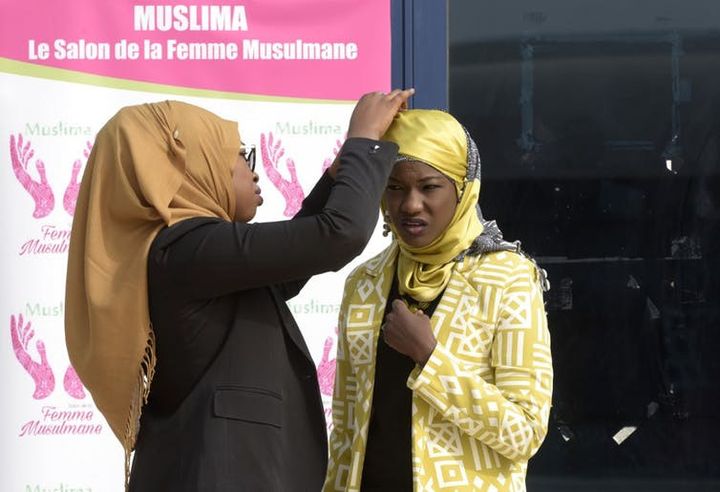 Des musulmanes sénégalaises s’entraident pour ajuster leur hijab à leur arrivée à la conférence presse en 2016 à l’occasion de Journée mondiale du Hijab, le 1ᵉʳ&nbsp;février. (SEYLLOU / AFP)