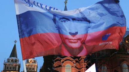 Un drapeau russe à l'effigie de Vladimir Poutine flotte sur la place du Manège, dans le centre de&nbsp;Moscou, le 5 mars 2012. Déjà président entre 1999 et 2008, l'ancien officier du KGB a été élu chef de l'Etat dès le premier tour&nbsp;la veille, après un intérim de quatre ans en tant que Premier ministre de Dmitri Medvedev. (ALEXANDER NEMENOV / AFP)