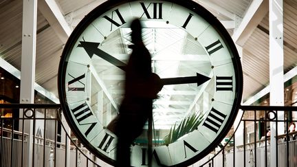 Un homme passe devant une horloge géante à Dijon le 25 mars 2010. (JEFF PACHOUD / AFP)