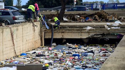 Des personnes utilisent des pompes pour tenter de vider la boue qui s'est accumulée sous un pont, à Alfafar, près de Valence, en Espagne, le 4 novembre 2024. (JOSE JORDAN / AFP)