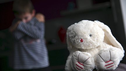 Un enfant prostré et une peluche. Photo d'illustration. (LIONEL VADAM / MAXPPP)