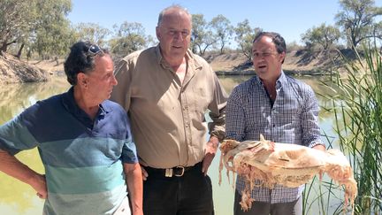 Dans une vidéo diffusée le 10 janvier 2019, le député australien de Nouvelle-Galles du Sud, Jeremy Buckingham (droite), tient dans ses mains une morue de Murray morte, au bord de la Darling River à Menindee (Australie). (OFFICE OF JEREMY BUCKINGHAM MLC / AFP)