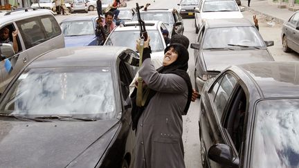 Une opposante au gouvernement tire en l'air avec son AK-47 &agrave; l'annonce de la d&eacute;mission du leader lybien Mouammar Kadhafi &agrave; Benghazi, le 19 mars 2011. (GORAN TOMASEVIC / REUTERS)