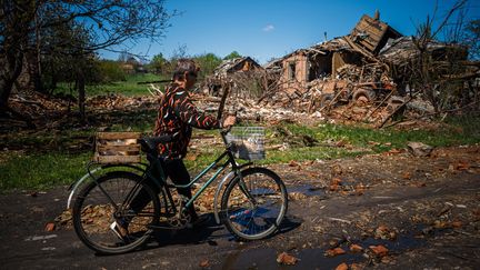 Une habitante de Siversk, dans la région ukrainienne de Donetsk, passe devant une maison détruite, le 2 mai 2023. (DIMITAR DILKOFF / AFP)