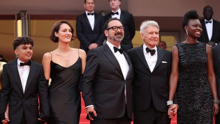 Harrison Ford entouré de l'équipe d'"Indiana Jones et le cadran de la destinée", avec à sa gauche Shaunette Renée Wilson et à sa droite le réalisateur du film James Mangold, l'actrice Phoebe Waller-Bridge, et le jeune acteur français Ethann Isidore. (MIKE COPPOLA / GETTY IMAGES EUROPE)