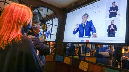 Dans une brasserie du 18e arrondissement de Paris le 14 octobre 2020, des clients regardent l'allocution télévisée du président Emmanuel Macron. (FREDERIC DUGIT / PHOTOPQR / LE PARISIEN / MAXPPP)