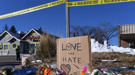 Des bouquets de fleurs et une pancarte où il est inscrit "L'amour plus fort que la haine" près du Club Q, où une fusillade a fait cinq morts et une vingtaine de blessés, dans le Colorado (Etats-Unis). (JASON CONNOLLY / AFP)