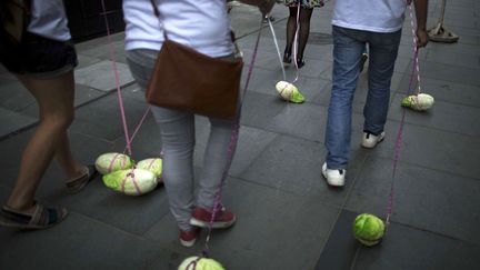 De jeunes Chinois prom&egrave;nent de faux choux lors d'une performance artistique sens&eacute;e encourager les libert&eacute;s individuelles &agrave; P&eacute;kin (Chine), le 24 juin 2014. (ALEXANDER F. YUAN / AP / SIPA)