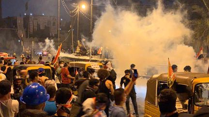 Des policiers font face aux manifestants et font usage de gaz lacrymogènes sur la place Tahrir de Bagdad, en Irak, le 30 octobre 2019. (MURTADHA SUDANI / ANADOLU AGENCY / AFP)