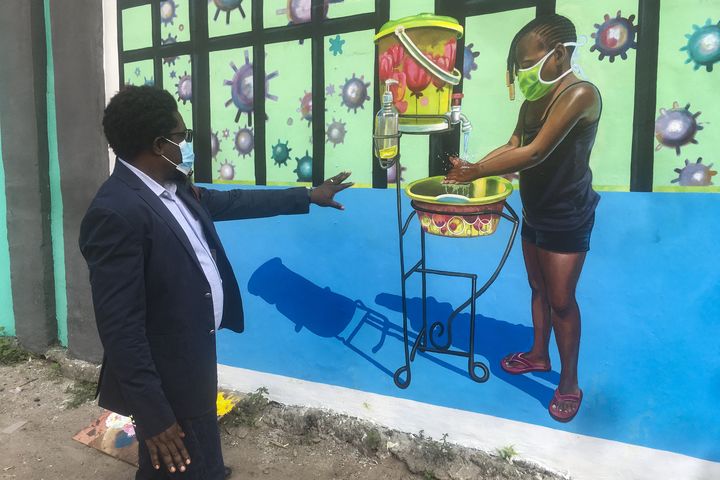 Henri Kalam Akulez, directeur de l'Académie des Beaux-Arts de Kinshasa devant une fresque visant à lutter contre la propagation du coronavirus, 18 juin 2020 (SAMIR TOUNSI / AFP)