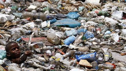 Un jeune gar&ccedil;on de 9 ans collecte des mat&eacute;riaux recyclables en pataugeant dans un canal, &agrave; Recife (Br&eacute;sil), le 24 octobre 2013. (REUTERS)