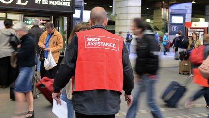 Un employ&eacute; de la SNCF aide des voyageurs lors de la gr&egrave;ve, &agrave; la gare Montparnasse, &agrave; Paris, le 20 juin 2014. (DOMINIQUE FAGET / AFP)