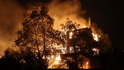 Une maison brûle dans le village de Varnavas, au nord d'Athènes (Grèce), le 11 août 2024. (COSTAS BALTAS / AFP)