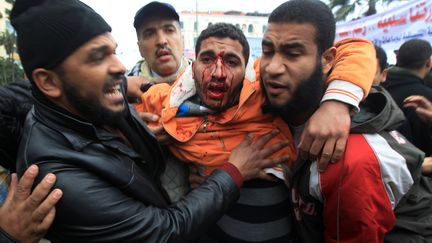 Des &Eacute;gyptiens aident un manifestant lors d'affrontements entre pro et anti-Mohamed Morsi, le 21 d&eacute;cembre 2012 &agrave; Alexandrie (Egypte). (MAHMUD HAMS / AFP)