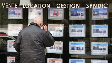 Un homme regarde des annonces dans la vitrine d'une agence immobilière. Photo d'illustration. (PASCAL PAVANI / AFP)