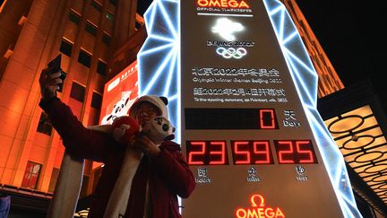 Une personne se prenant en selfie devant l'horloge annonçant le début des Jeux olympiques d'hiver de Pékin, dans la capitale chinoise. (JADE GAO / AFP)