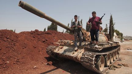 Des rebelles syriens sur un tank de l'arm&eacute;e captur&eacute; par l'opposition, non loin d'Alep (Syrie). (AHMAD GHARABLI / AFP)