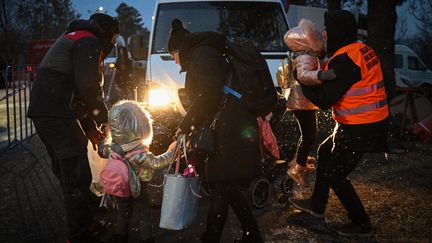 Des enfants ukrainiens et leurs parents sont aidés à monter dans un bus au poste frontière de Siret avec l'Ukraine, dans la ville de Siret, le 1er mars 2022. (DANIEL MIHAILESCU / AFP)