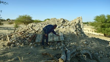 Un homme examine les ruines d’un mausolée détruit par les islamistes, dans un cimetière de Tombouctou, en juillet 2013 (ERIC FEFERBERG / AFP)